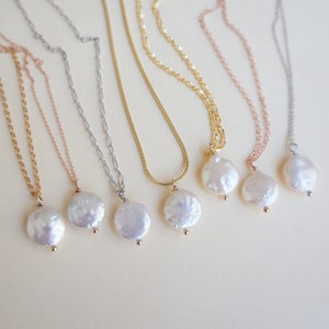 May include: Five necklaces with different chain styles and pearl pendants. The pearls are all round and white, and the chains are gold, silver, and rose gold.