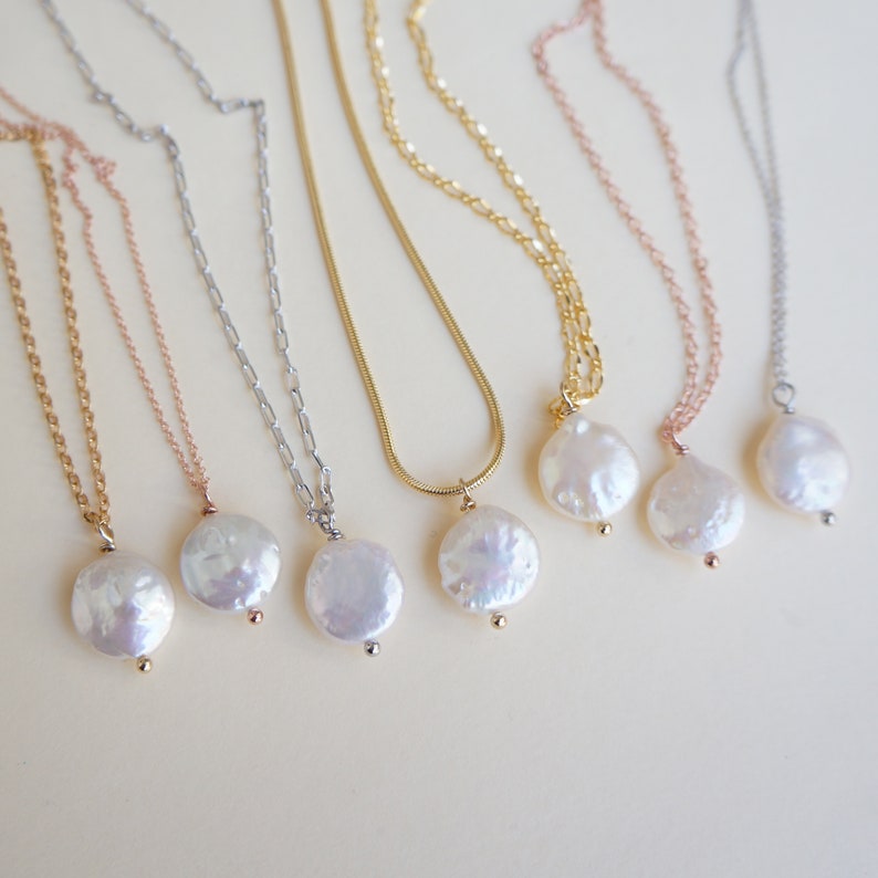 May include: Five necklaces with different chain styles and pearl pendants. The pearls are all round and white, and the chains are gold, silver, and rose gold.