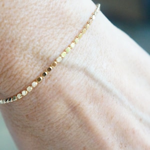 Puede incluir: Un delicado brazalete de cadena de oro con un dise&ntilde;o simple y minimalista. El brazalete est&aacute; hecho de peque&ntilde;os eslabones redondos que est&aacute;n espaciados uniformemente.