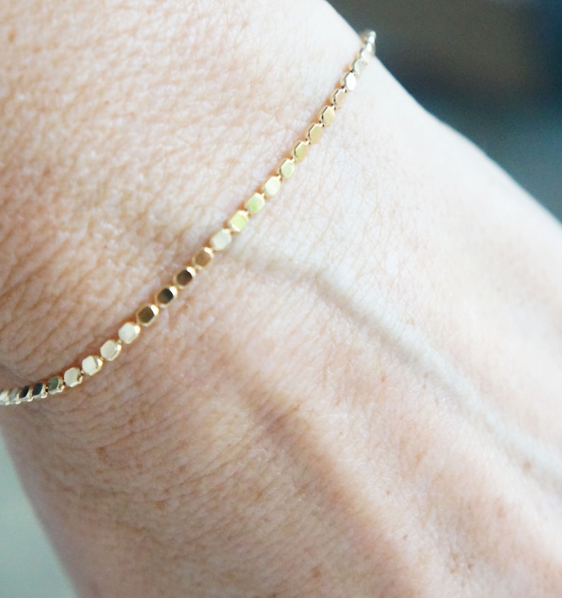 Puede incluir: Un delicado brazalete de cadena de oro con un dise&ntilde;o simple y minimalista. El brazalete est&aacute; hecho de peque&ntilde;os eslabones redondos que est&aacute;n espaciados uniformemente.