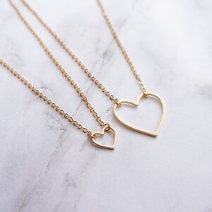 Puede incluir: Dos collares de oro con colgantes de coraz&oacute;n abierto. El colgante m&aacute;s grande es un simple coraz&oacute;n abierto, mientras que el colgante m&aacute;s peque&ntilde;o tiene una forma de coraz&oacute;n m&aacute;s detallada.