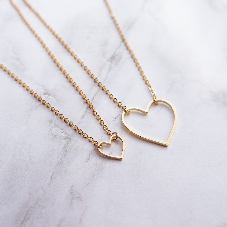 Puede incluir: Dos collares de oro con colgantes de coraz&oacute;n abierto. El colgante m&aacute;s grande es un simple coraz&oacute;n abierto, mientras que el colgante m&aacute;s peque&ntilde;o tiene una forma de coraz&oacute;n m&aacute;s detallada.