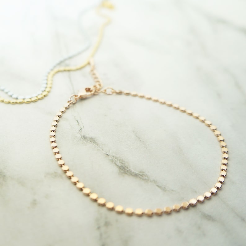 Puede incluir: Un delicado brazalete de cadena dorada con un dise&ntilde;o de eslabones cuadrados. El brazalete est&aacute; hecho de una cadena fina y tiene un aspecto simple y elegante.