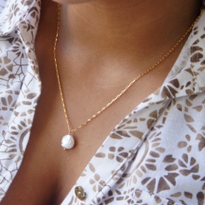May include: A gold chain necklace with a large, white pearl pendant.