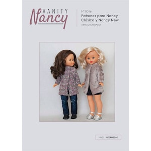 Puede incluir: Un patrón para hacer un abrigo para una muñeca Nancy. El patrón es para un nivel de habilidad intermedio. La imagen muestra dos muñecas Nancy con el abrigo. Una muñeca tiene el pelo castaño y lleva un abrigo rosa y blanco. La otra muñeca tiene el pelo rubio y lleva un abrigo gris.
