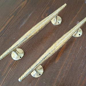 Könnte beinhalten: Zwei verzierte goldene Türklinken mit aufwendigen floralen Mustern. Die Griffe sind aus Metall und haben eine polierte Oberfläche.