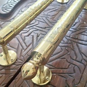 Könnte beinhalten: Zwei verzierte goldene Türklinken mit aufwendigen gravierten Designs. Die Griffe sind aus Messing und haben eine polierte Oberfläche.