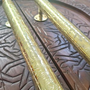 May include: A pair of ornate gold door handles with intricate floral patterns. The handles are made of metal and have a polished finish.