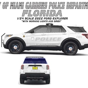 Op de afbeelding: Een wit 1:24 schaalmodel van een 2022 Ford Explorer politie-SUV met werkende lichten en sirene. Het model heeft zwarte wielen en de tekst "POLICE" op de zijkant. De afbeelding toont ook het logo van de politie van Miami Gardens.