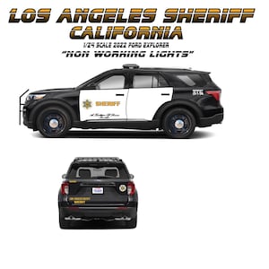May include: A black and white 1/24 scale model of a Los Angeles Sheriff Ford Explorer. The model has the text "LOS ANGELES SHERIFF CALIFORNIA" and "NON WORKING LIGHTS". The model has the Sheriff logo on the side.