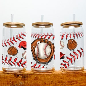 May include: Three clear glass tumblers with bamboo lids and straws. Each tumbler features a baseball-themed design with red stitching, baseballs, gloves, and hats.