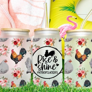 May include: Three frosted glass tumblers with lids and straws. Each tumbler features a floral pattern with roosters and hens. The middle tumbler has a black circle with the text "Rise & shine Mothercluckers".