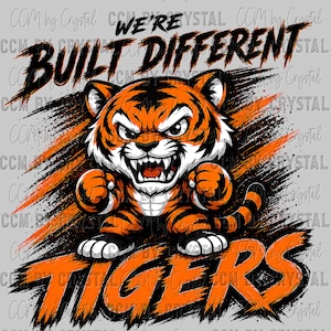 May include: A graphic illustration of an angry cartoon tiger with orange and black stripes, baring its teeth and clenching its fists. The text WE'RE BUILT DIFFERENT appears above the tiger, and the word TIGERS is printed in orange below it.