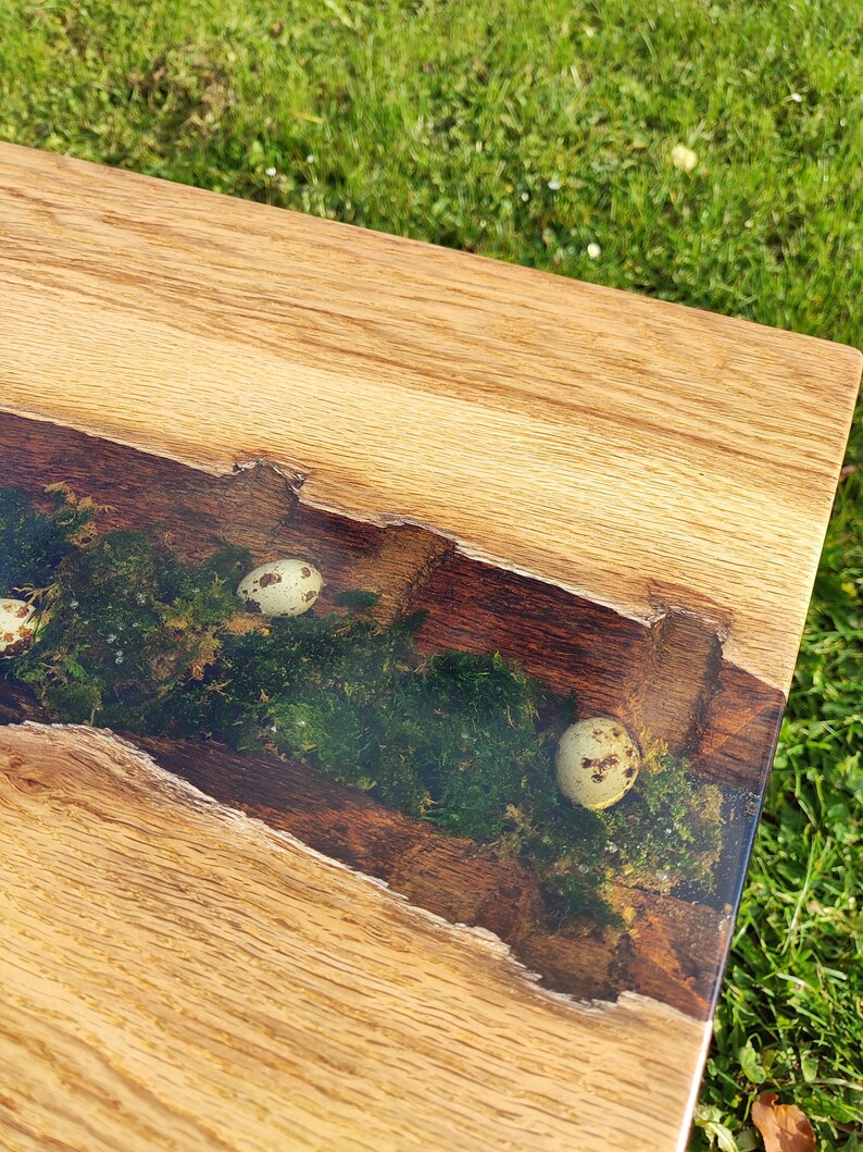 Pode incluir: Um tampo de mesa de madeira com uma incrusta&ccedil;&atilde;o de resina ep&oacute;xi transparente. A incrusta&ccedil;&atilde;o apresenta um desenho de musgo verde com pequenos ovos de codorniz brancos.