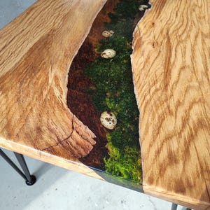 Pode incluir: Uma mesa de madeira com uma borda viva e uma incrusta&ccedil;&atilde;o de rio de resina. A resina &eacute; verde e tem ovos brancos salpicados embutidos nela. A mesa tem pernas de cabelo de metal preto.