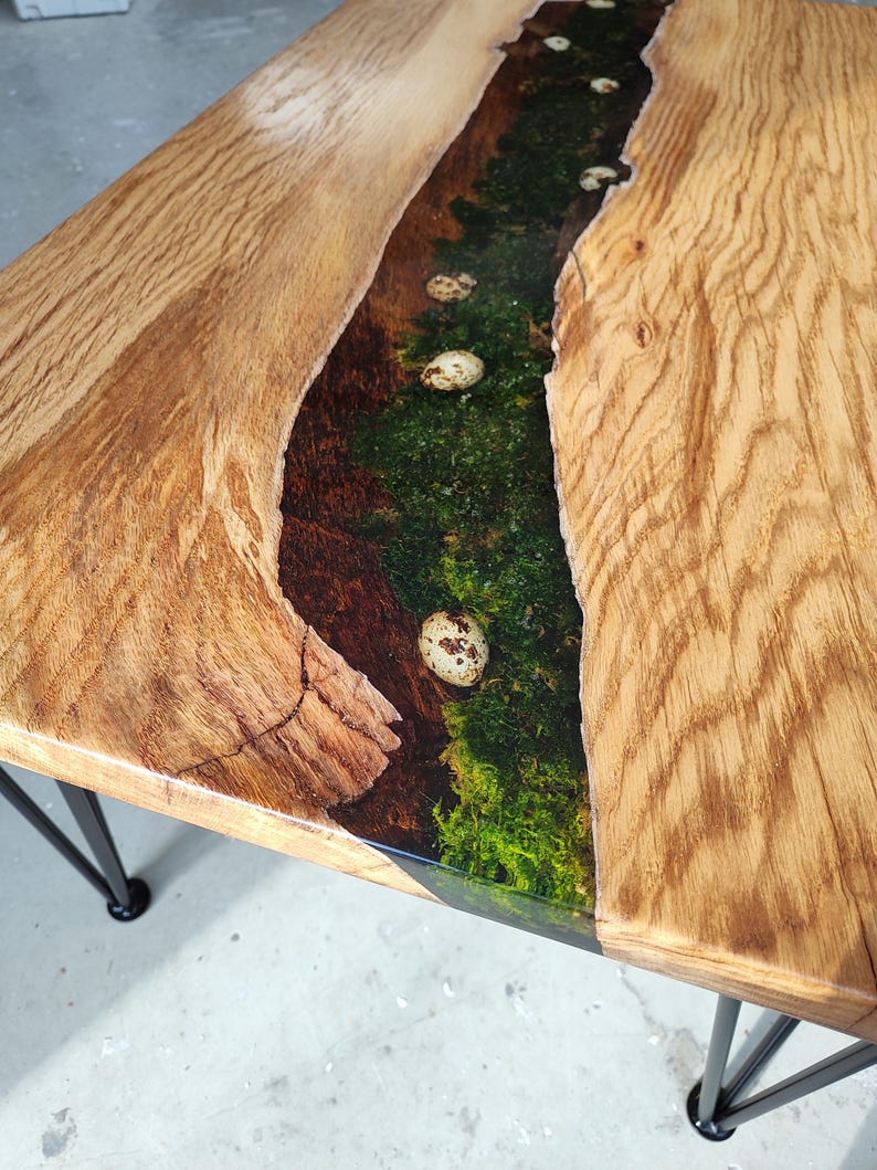 Pode incluir: Uma mesa de madeira com uma borda viva e uma incrusta&ccedil;&atilde;o de rio de resina. A resina &eacute; verde e tem ovos brancos salpicados embutidos nela. A mesa tem pernas de cabelo de metal preto.