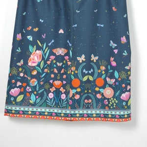 Könnte beinhalten: Dunkelblauer Rock mit elastischem Bund, verziert mit einem lebendigen Blumen- und Schmetterlingsmuster. Das Design zeigt bunte Blumen, Schmetterlinge und Libellen auf dunklem Hintergrund, mit einem dekorativen Saum.