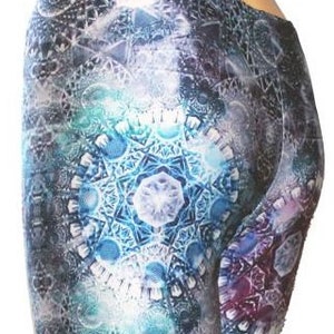 May include: Close-up of a pair of patterned shorts. The shorts feature a complex geometric design in shades of blue, teal, purple, and white. The pattern is centered on the back of the shorts and fades towards the edges.