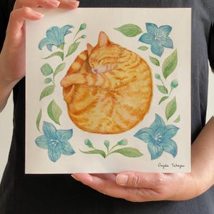 A tabby orange cat curled up with a happy face, surrounded by star-shaped blue flowers and green leaves.