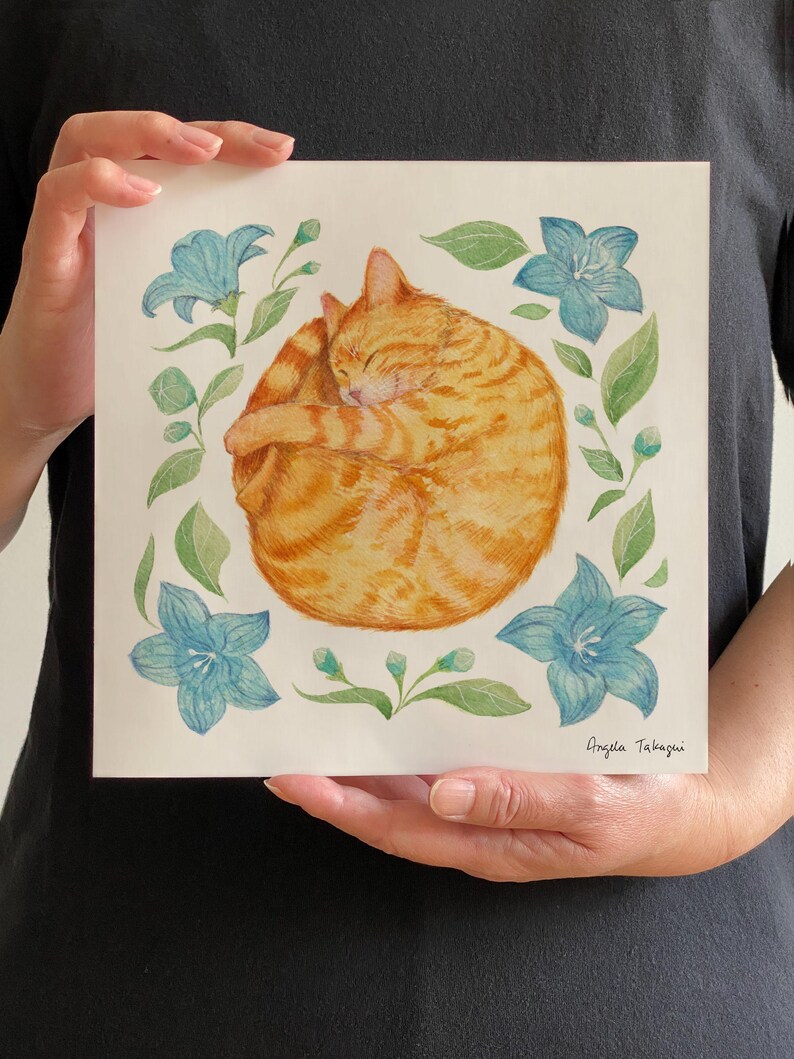 A tabby orange cat curled up with a happy face, surrounded by star-shaped blue flowers and green leaves.