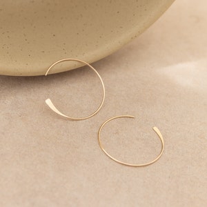 Peut inclure: Deux boucles d'oreilles créoles en or avec un design simple et minimaliste. Les boucles d'oreilles sont en métal fin et ont une forme légèrement incurvée.