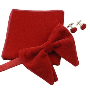 May include: A red velvet bow tie set with a matching pocket square and cufflinks. The bow tie is pre-tied and has a classic shape. The pocket square is a small square of fabric that can be folded and placed in a jacket pocket. The cufflinks are silver with red velvet accents.