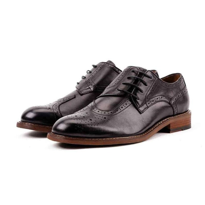 May include: A pair of black leather lace-up shoes with a brogue design. The shoes have a brown leather sole and a rounded toe.
