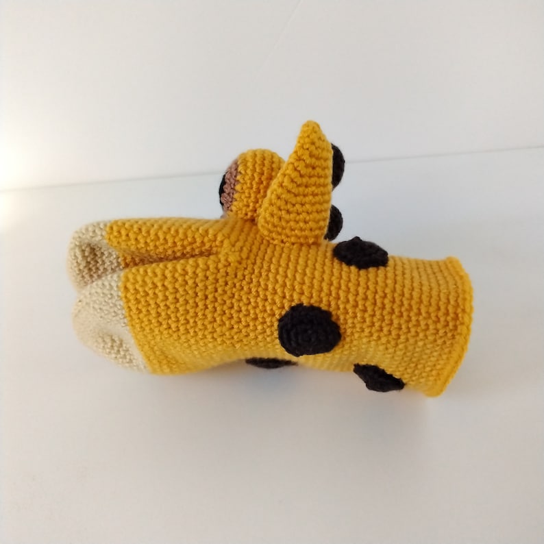 May include: A crocheted giraffe toy with black spots and a yellow and beige color scheme.