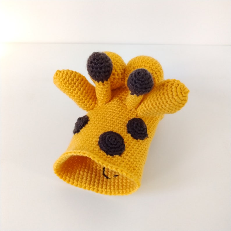 May include: A crocheted giraffe toy with a yellow body and black spots. The giraffe has a long neck and a small head with black eyes.