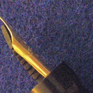 May include: Close-up of a gold-toned fountain pen nib with a fine point.