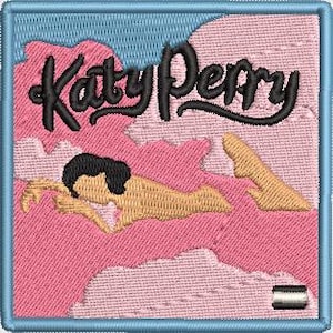 Könnte beinhalten: Ein gestickter Patch in Rosa und Blau mit einer Frau, die auf Wolken liegt, und dem Text "Katy Perry" in schwarzer Kursivschrift.