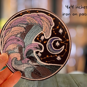 May include: Embroidered iron-on patch featuring a crescent moon, stars, and a swirling wave design in shades of pink, blue, and brown. The patch measures 4x4 inches.