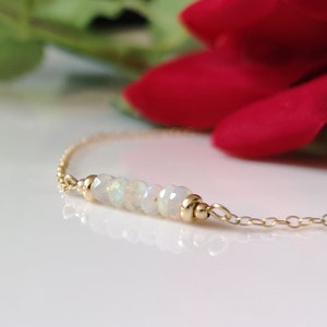 May include: A delicate gold chain bracelet with a row of white opal beads.