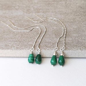 May include: A pair of silver chain earrings with green malachite teardrop-shaped stones.