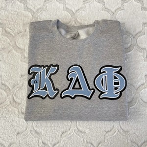 May include: Gray sweatshirt with a blue and white embroidered Greek letter design that reads "ΚΔΦ".