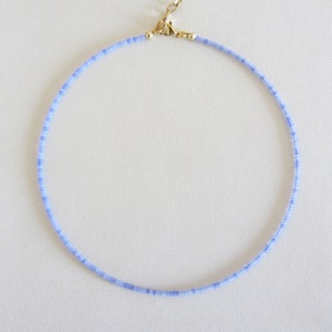 May include: A delicate light blue beaded necklace with a gold clasp.