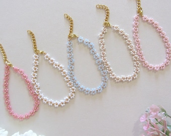 May include: Five delicate flower-shaped beaded necklaces in pink, white, and light blue. Each necklace has a gold clasp.