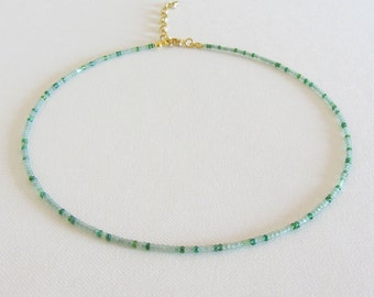 May include: A delicate green and blue beaded choker necklace with a gold clasp.