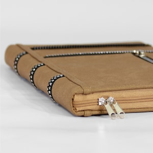 May include: A brown leather zippered pouch with a black trim and silver rhinestones. The pouch has two zipper pulls.