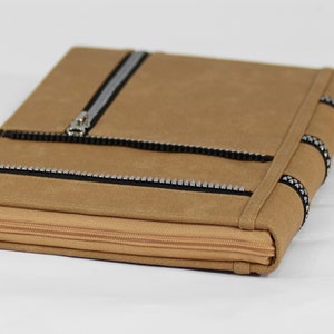 May include: A brown leather zippered pouch with black zipper pulls and silver studs. The pouch has a flap with a zipper closure.