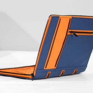May include: A blue laptop sleeve with orange zipper accents. The sleeve has a zippered pocket on the back.