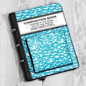 May include: A turquoise and white camouflage-patterned composition book with a black spine featuring zipper-like accents. The cover displays the text COMPOSITION BOOK, Creativity is very messy, and I'm very creative, WIDE RULED, 100 SHEETS, 200 PAGES, 9.75 INCH X 7.5 INCH.