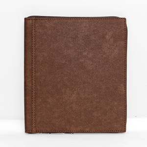 May include: A rectangular brown portfolio folder with a textured, leather-like finish. The folder features a vertical stitched seam along the left side and a dark brown zipper that runs along the right edge and top, securing the contents inside.