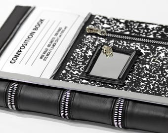 May include: A black and white composition book cover featuring a classic speckled pattern, a rectangular mirror with a zipper border, and a horizontal zipper pocket. The cover displays the text COMPOSITION BOOK, WIDE RULED, 100 SHEETS, 200 PAGES, 9.75 INCH X 7.5 INCH.