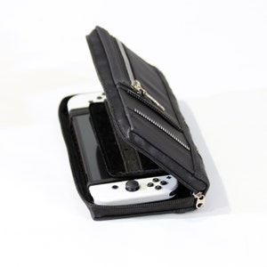 May include: A black zippered carrying case for a Nintendo Switch console. The case is open and the console is inside with the controller attached.