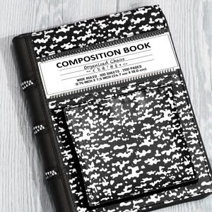 May include: A black and white composition book cover with a speckled pattern, featuring a central label that reads COMPOSITION BOOK, Organized Chaos, and WIDE RULED, 100 SHEETS, 200 PAGES, 24.7 cm x 19.0 cm. It includes a zip and a front pocket.