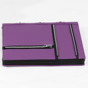 May include: Purple leather zippered notebook with three zippered pockets on the front.