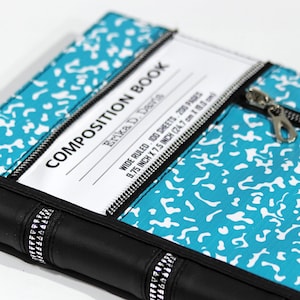 Könnte beinhalten: Ein Notizbuch mit einem türkis-weißen Spritzmuster. Auf dem Einband steht der Text "COMPOSITION BOOK" und "Erika D. Davis". Das Buch hat einen schwarzen Reißverschluss und Buchrücken. Maße: 24,7 cm x 19,1 cm.