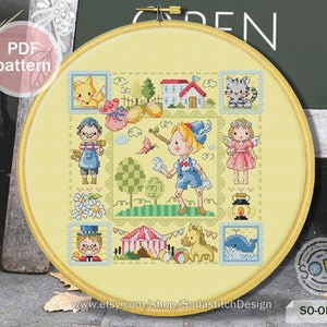 May include: A colorful cross-stitch pattern featuring a whimsical scene with children, animals, and a circus tent. The pattern is framed in a yellow hoop and includes the text "SO-OP3225".