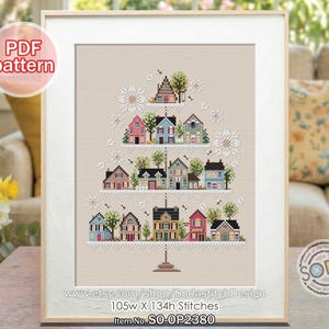 Op de afbeelding: Een ingelijst kruissteekpatroon met een gelaagd ontwerp van kleurrijke huizen met bomen en bloemmotieven. Het kunstwerk bevat de tekst "PDF pattern" en winkelgegevens. Het ontwerp is 105 steken breed en 134 steken hoog.